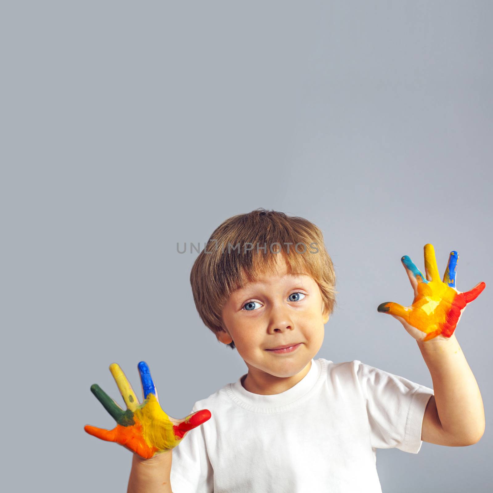 Little boy with hands painted in colorful paints ready for hand prints