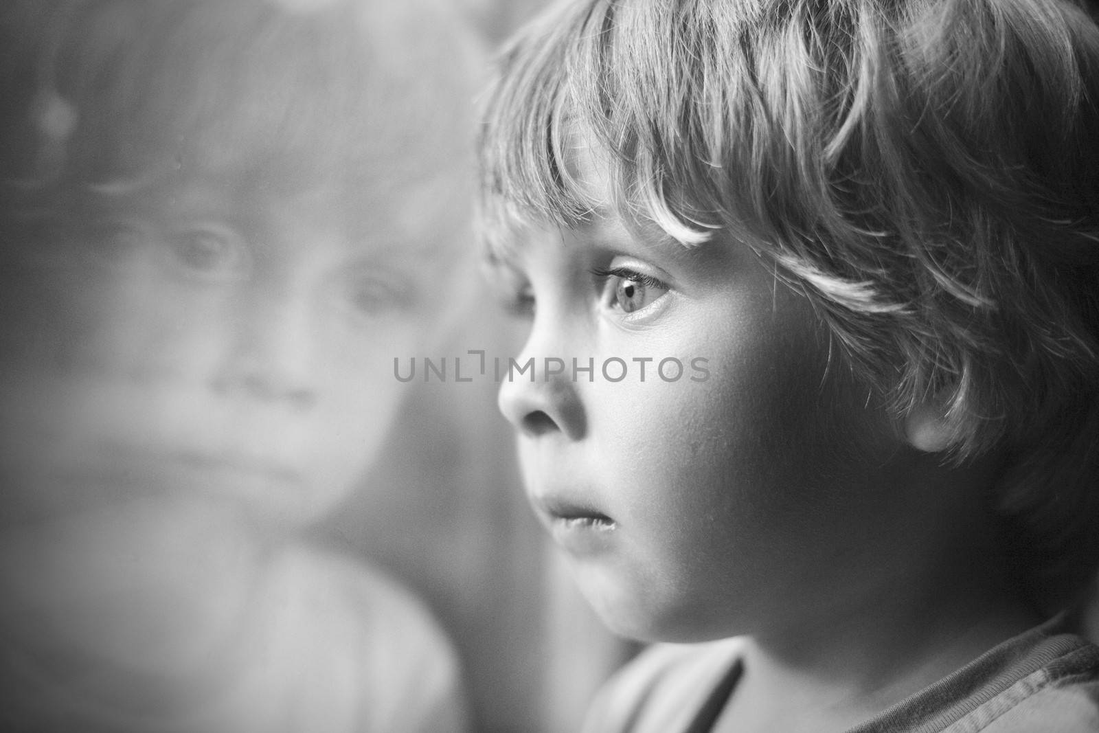 Little boy looking through window.