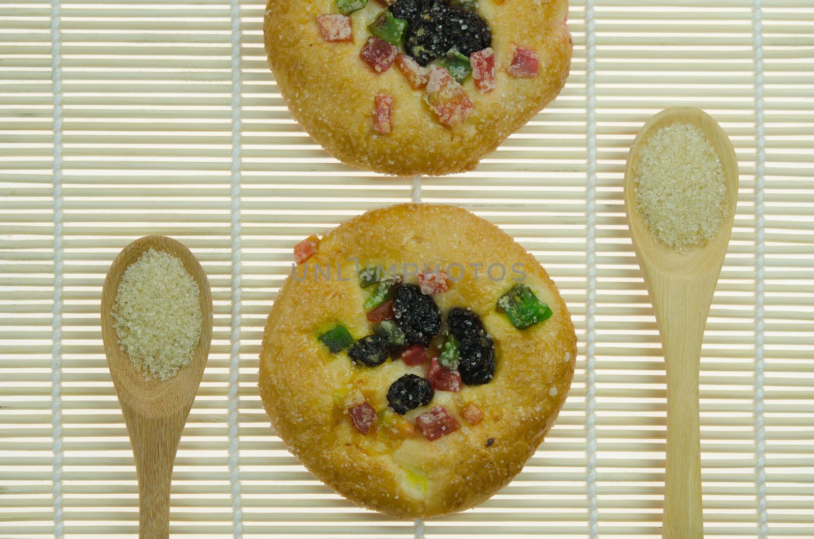 two  bread with raisin and  dried fruits and two spoon of sugar  on wooden background