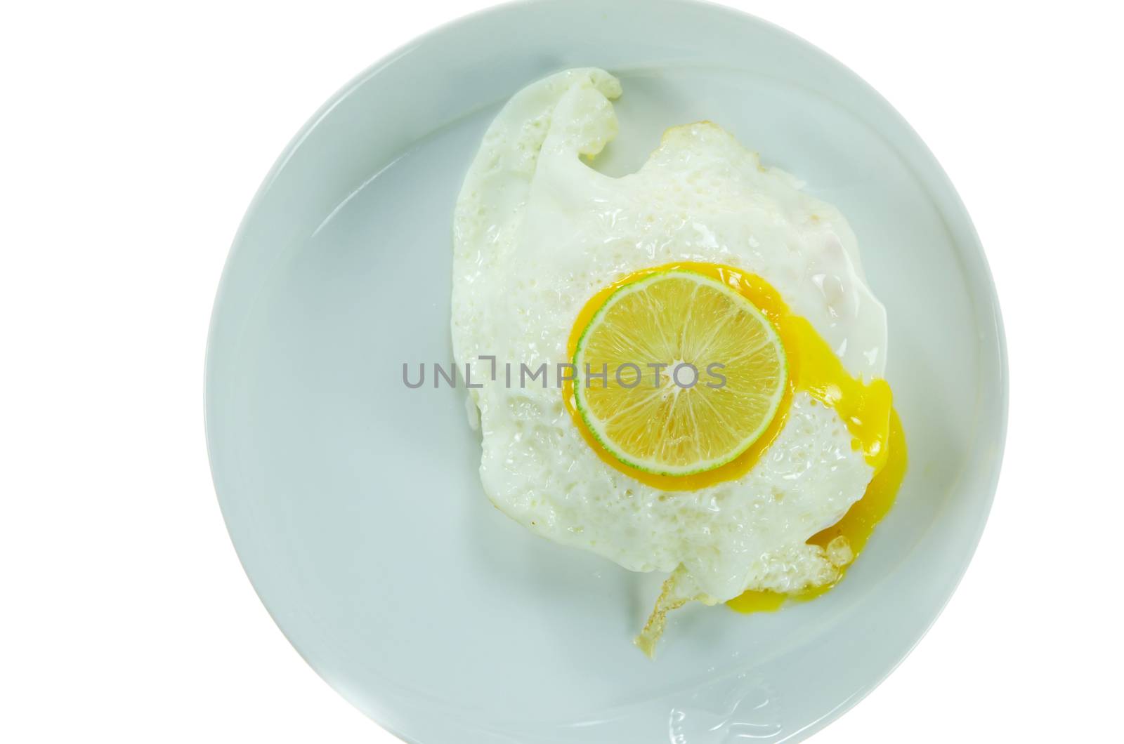 top view fried egg with slices of lime  on white dish over white background