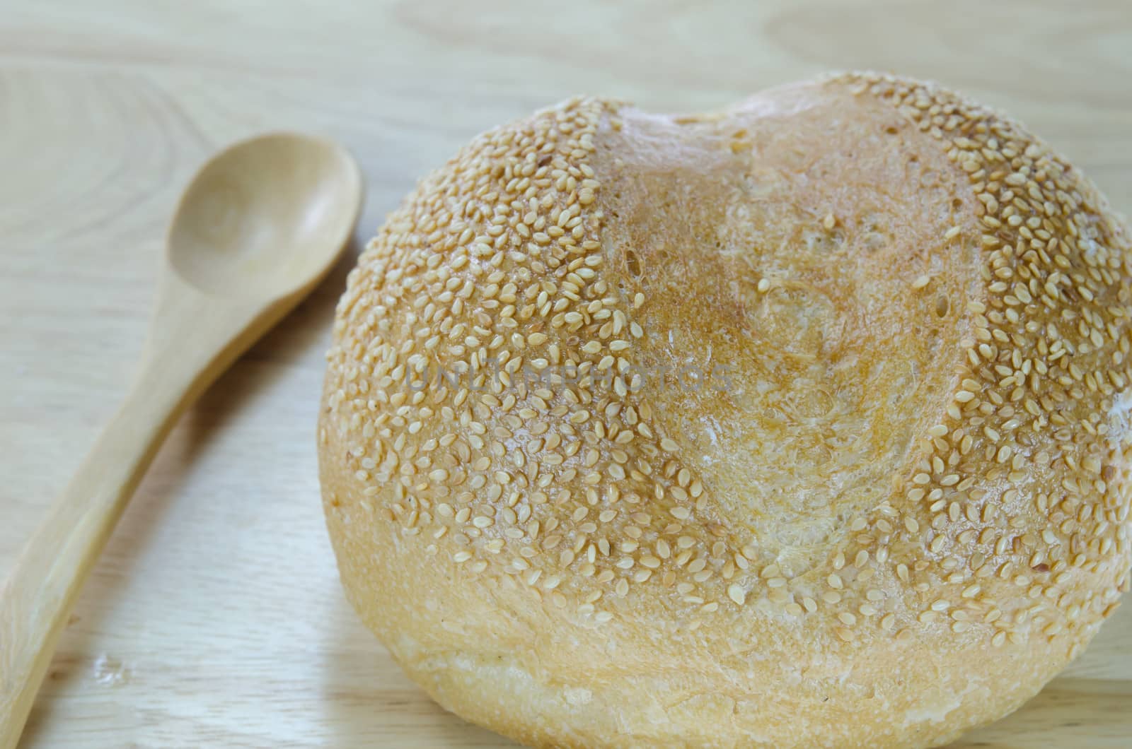 fresh rolls bread with sesame seeds with wooden spoon on wooden background