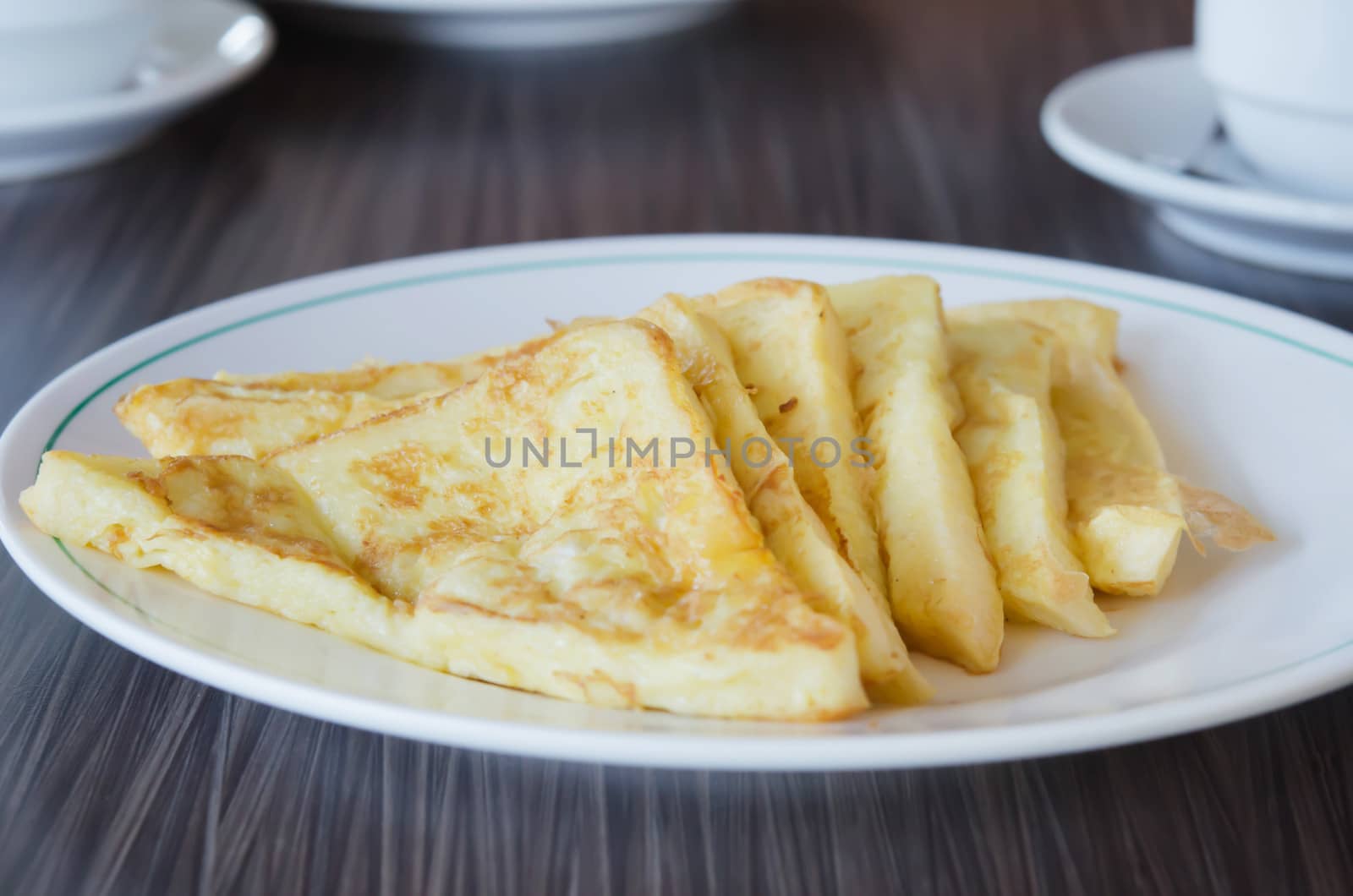 slices of french toast on  a white plate over wooden table