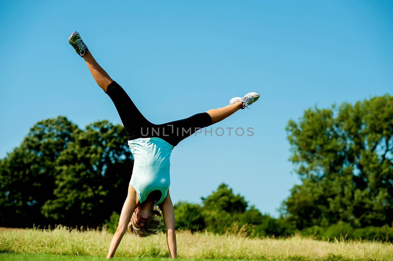 Young woman doing cartwheel at the green meadow