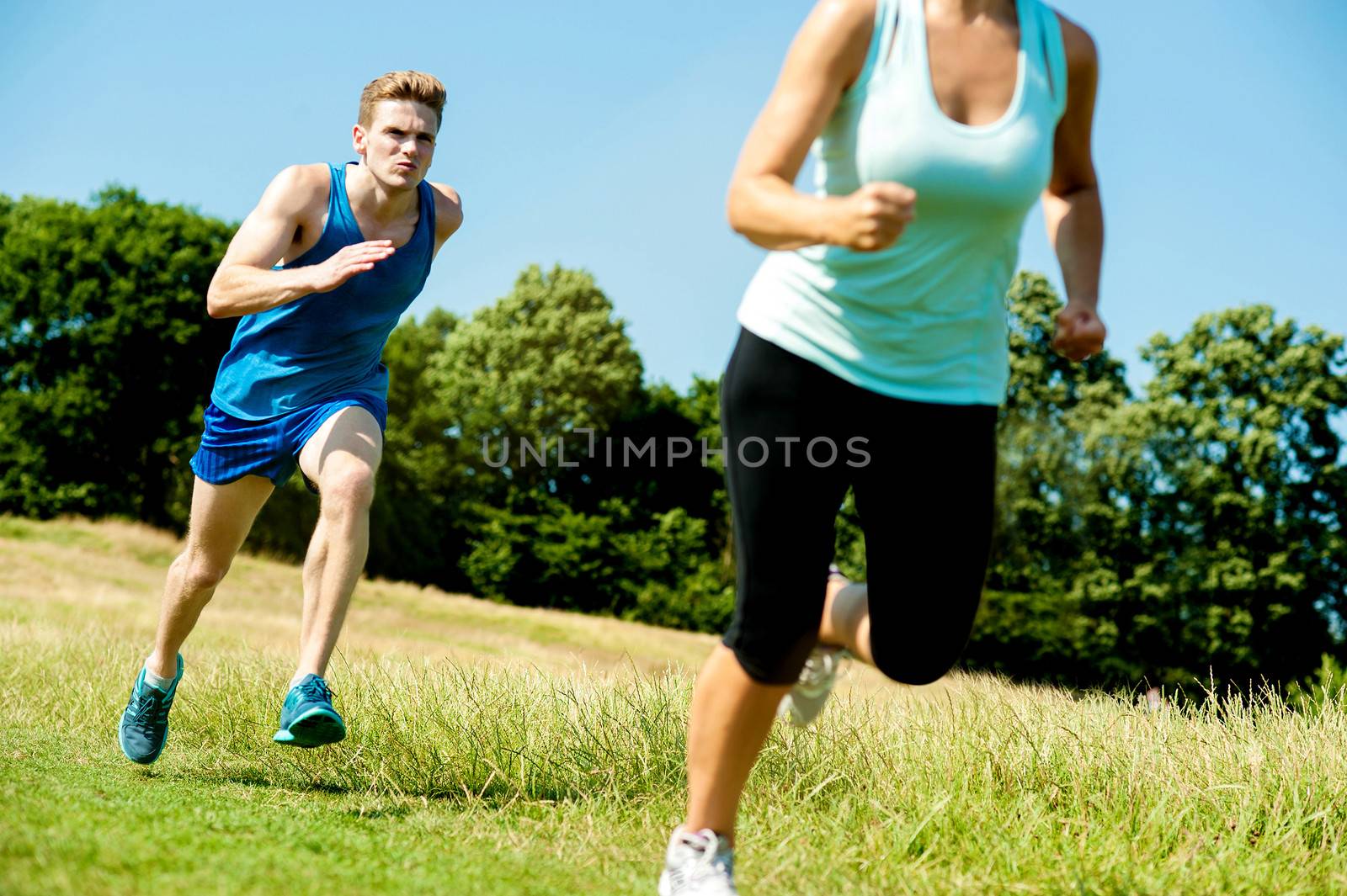 Two athletes running through meadows by stockyimages