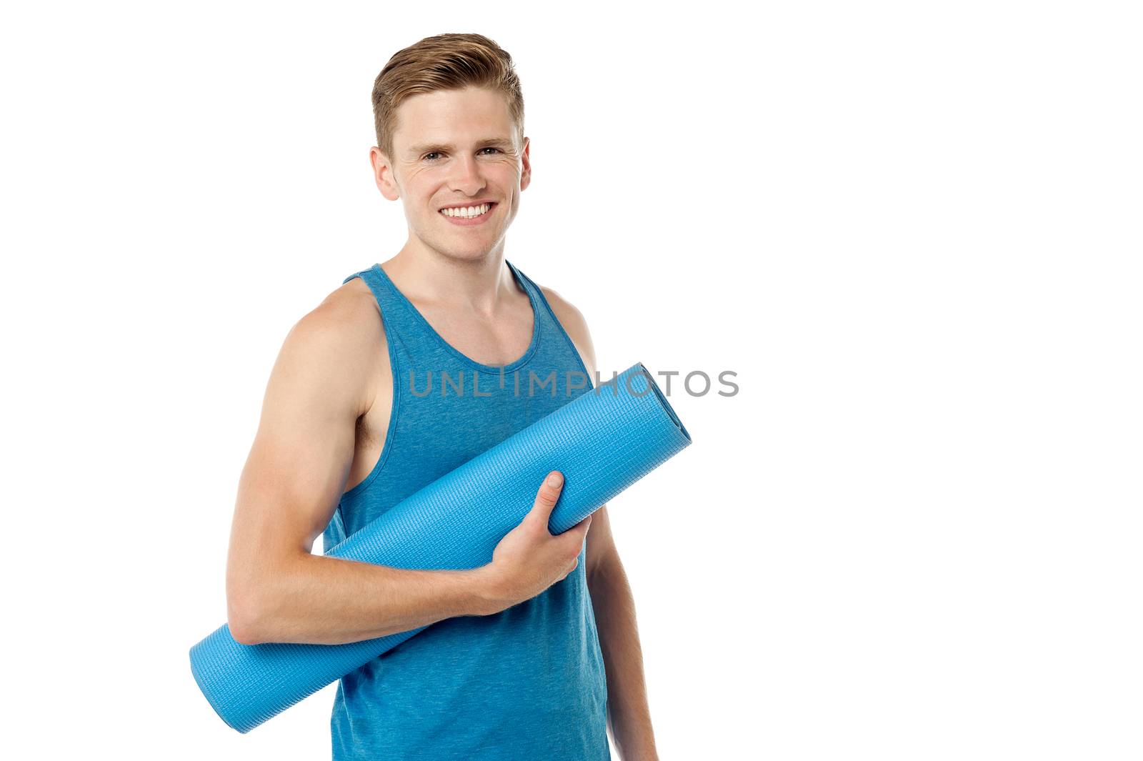 Smiling male fitness instructor holding blue mat
