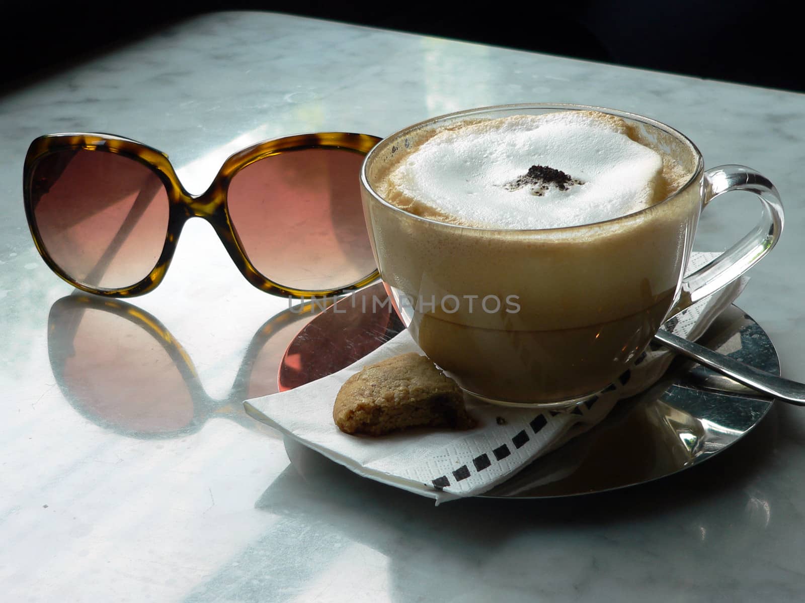 Cup of cappuccino coffee, biscuit and sunglasses