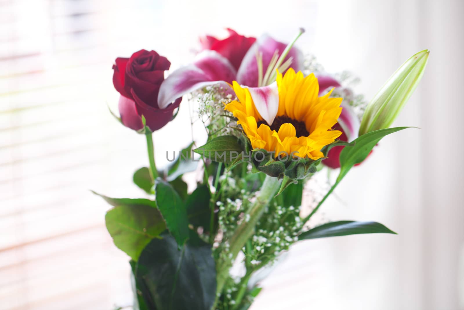 beautiful bouquet of sunflowers, lily and roses in a vase
