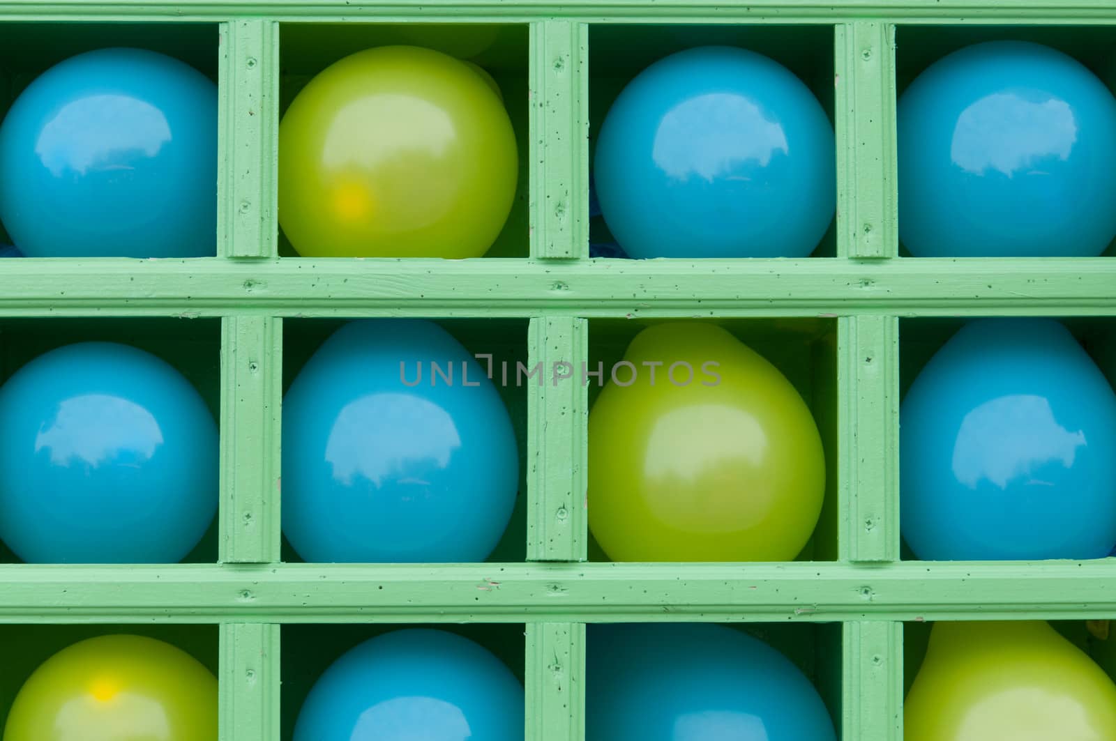 Blue and yellow inflatable balloons on shelves of wooden box.