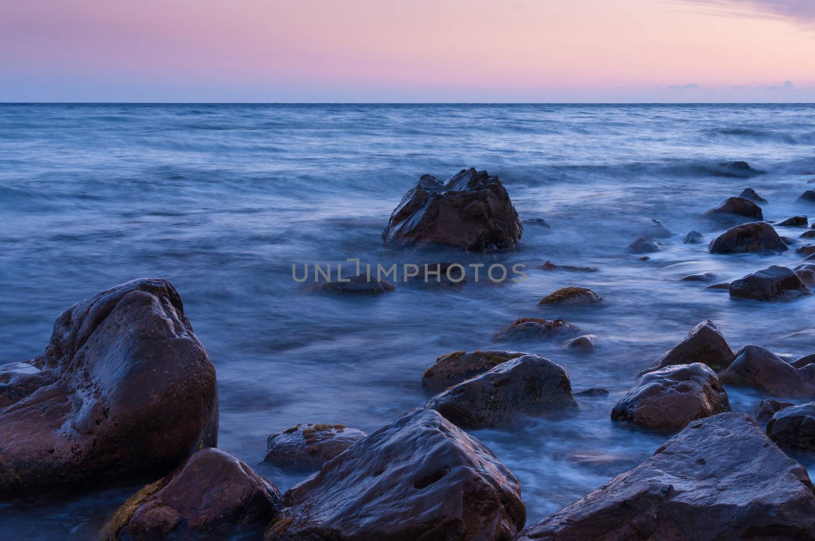 Sunset on sea. In foreground large boulders. by BPhoto