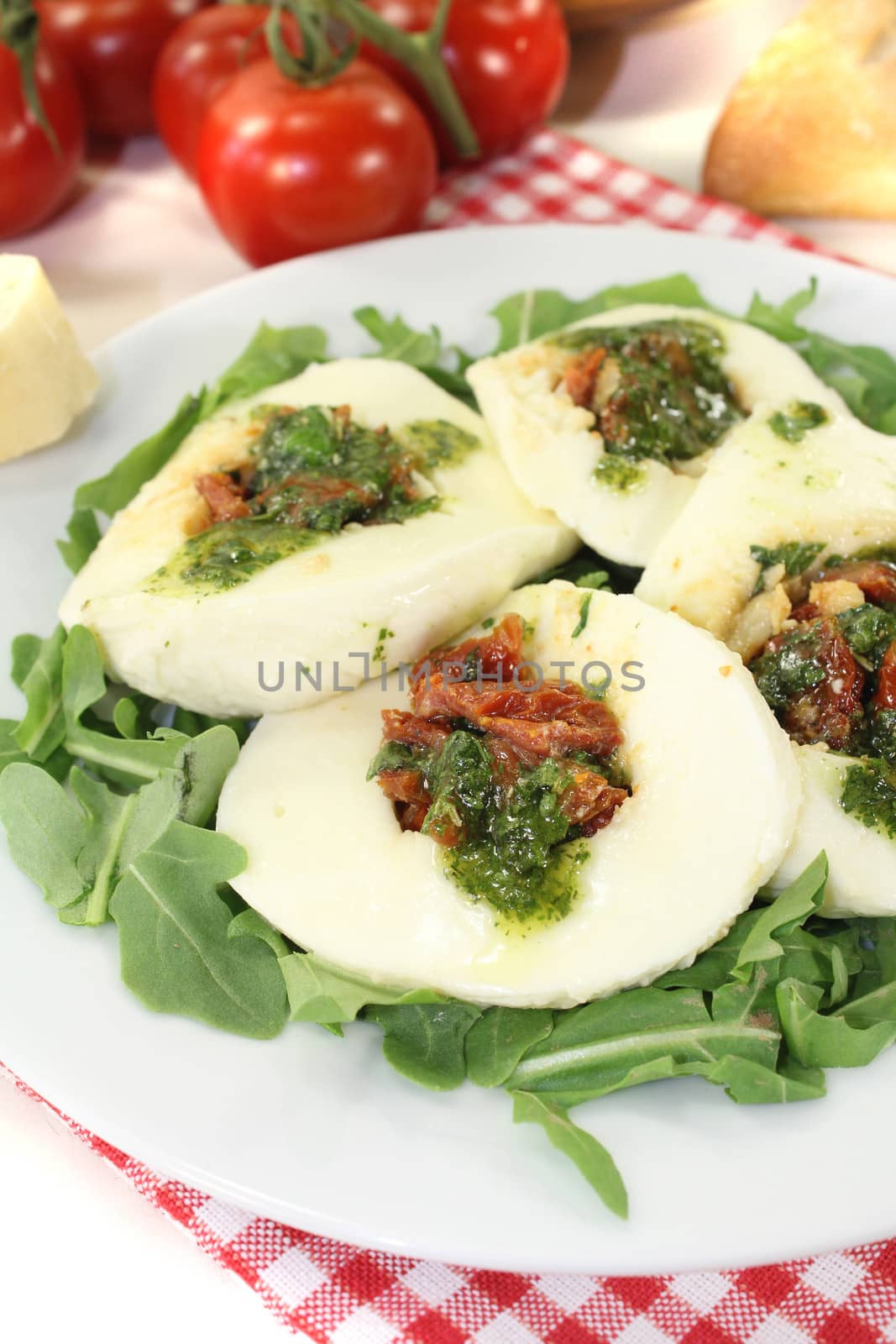 stuffed mozzarella with dried tomatoes and arugula on a light background