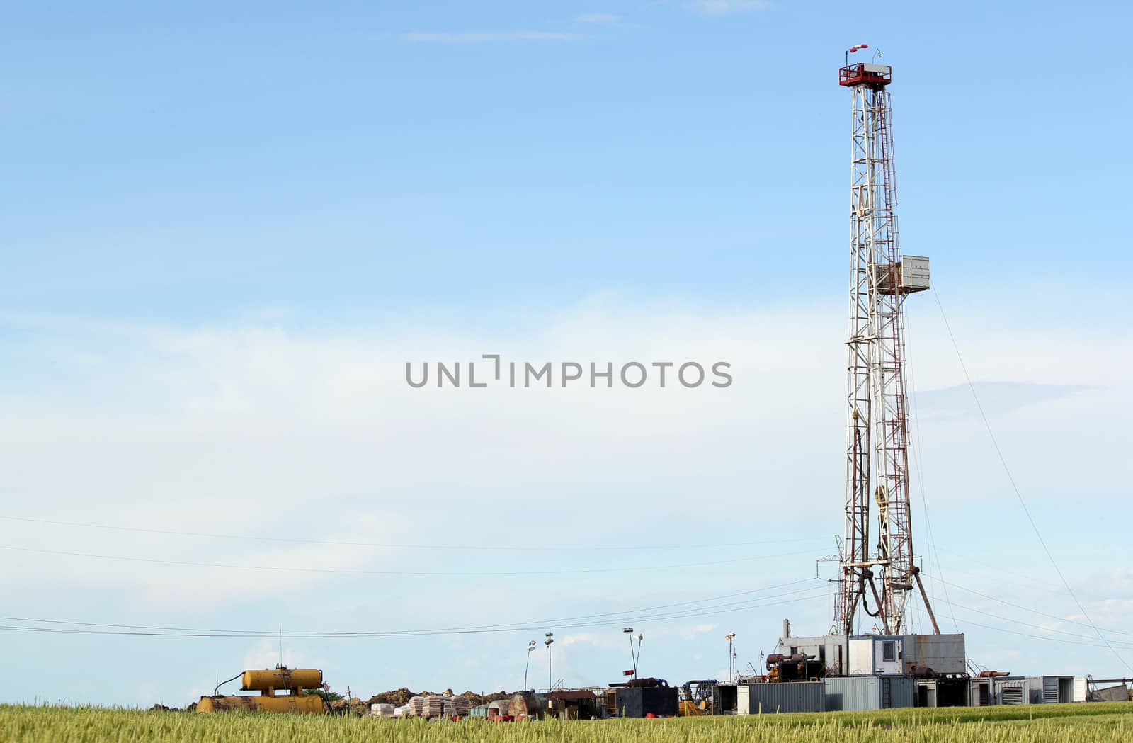 land oil drilling rig in green wheat field by goce