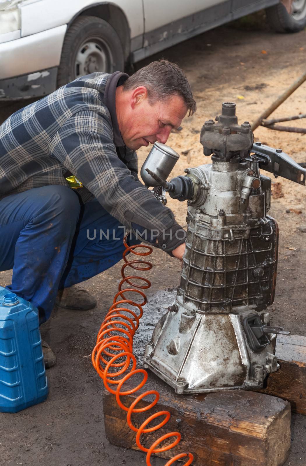 A man cleans the gearbox taken from the car for overhaul , without the help of professionals
