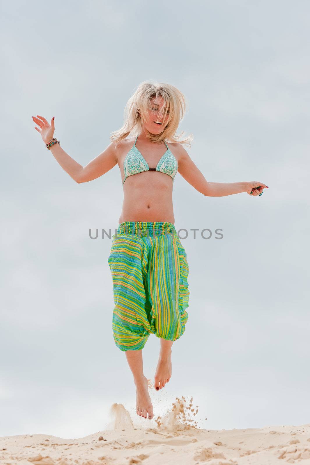 Young slim girl jumping in the sand.