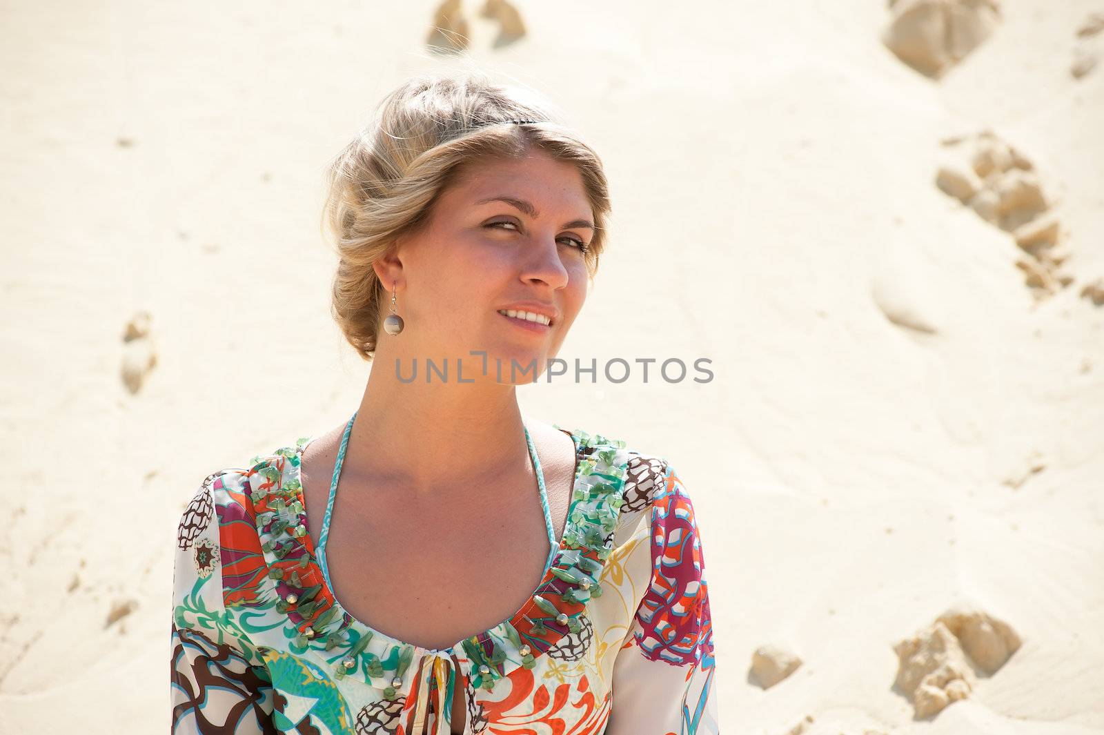 Portrait of a blonde in a sarafan on the background the sand dune.