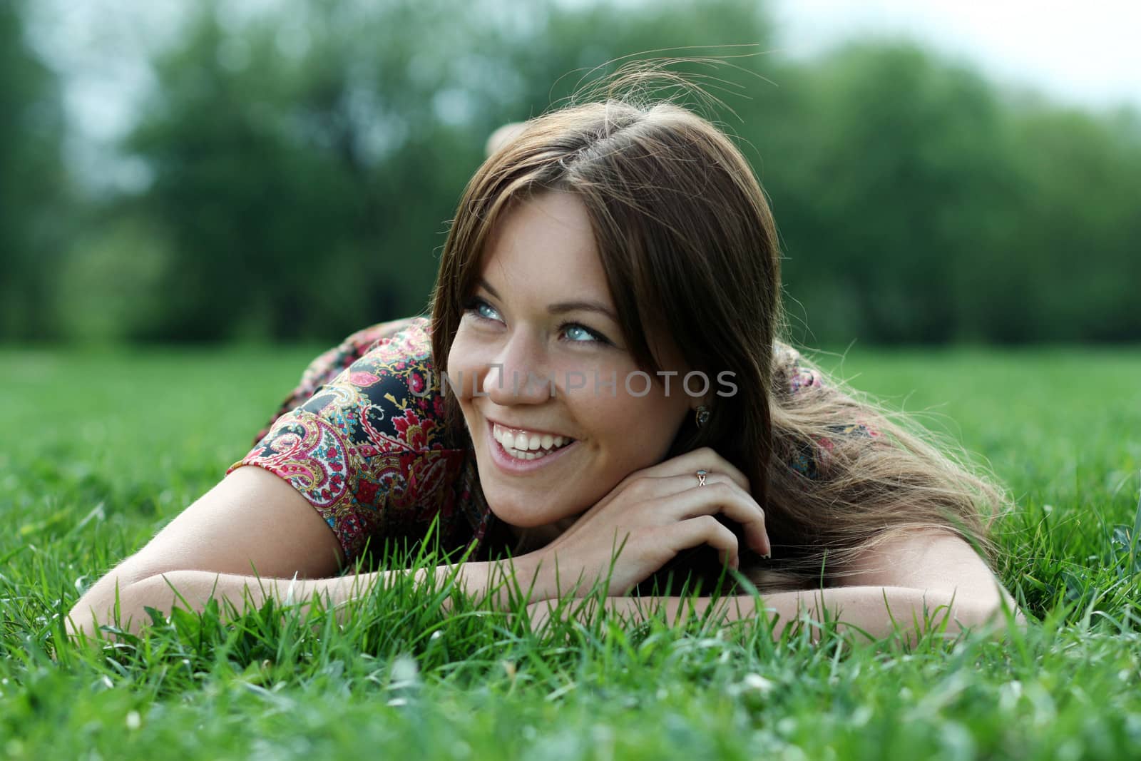 Portrait of young woman lying on a green lawn