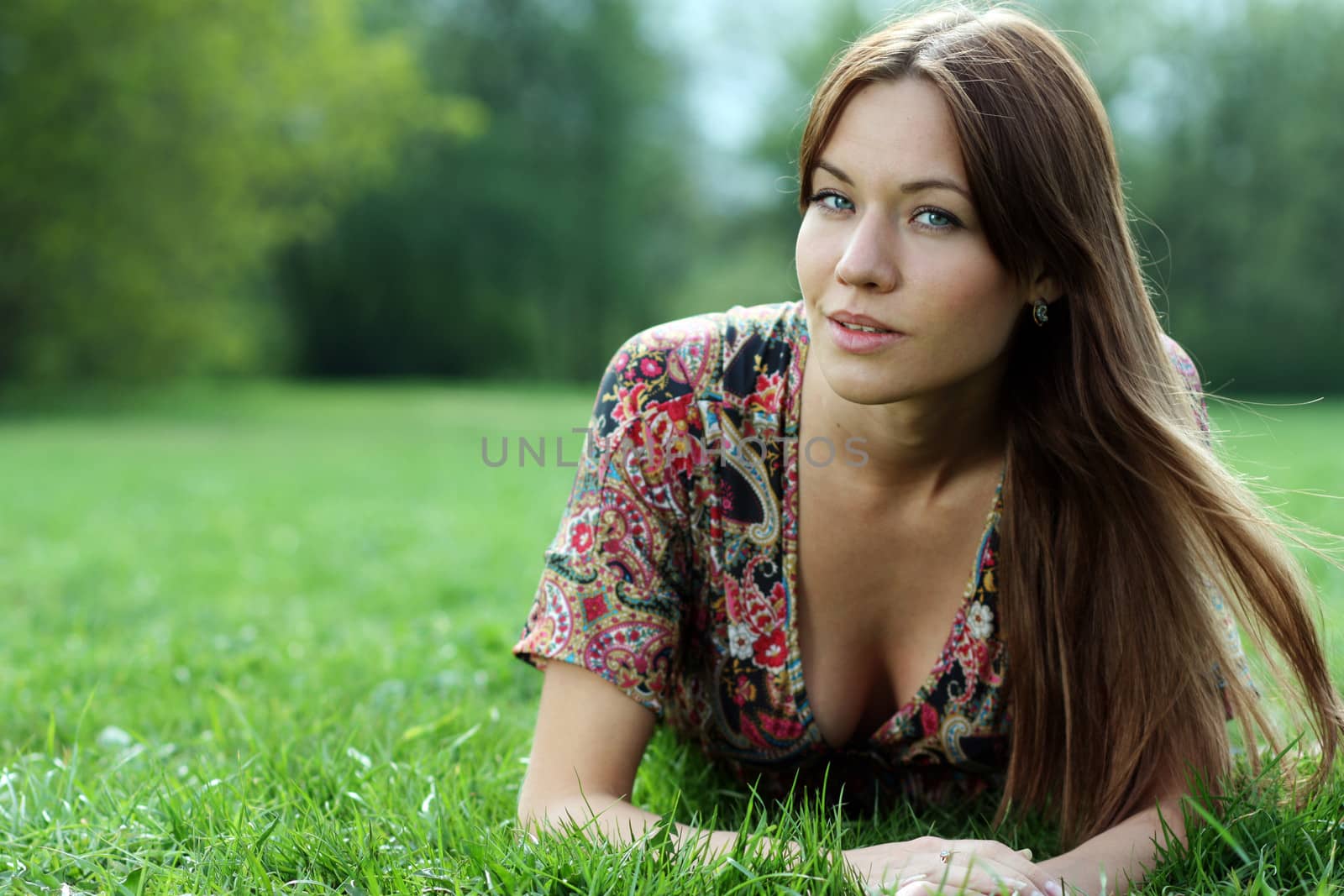 Portrait of young woman lying on a green lawn