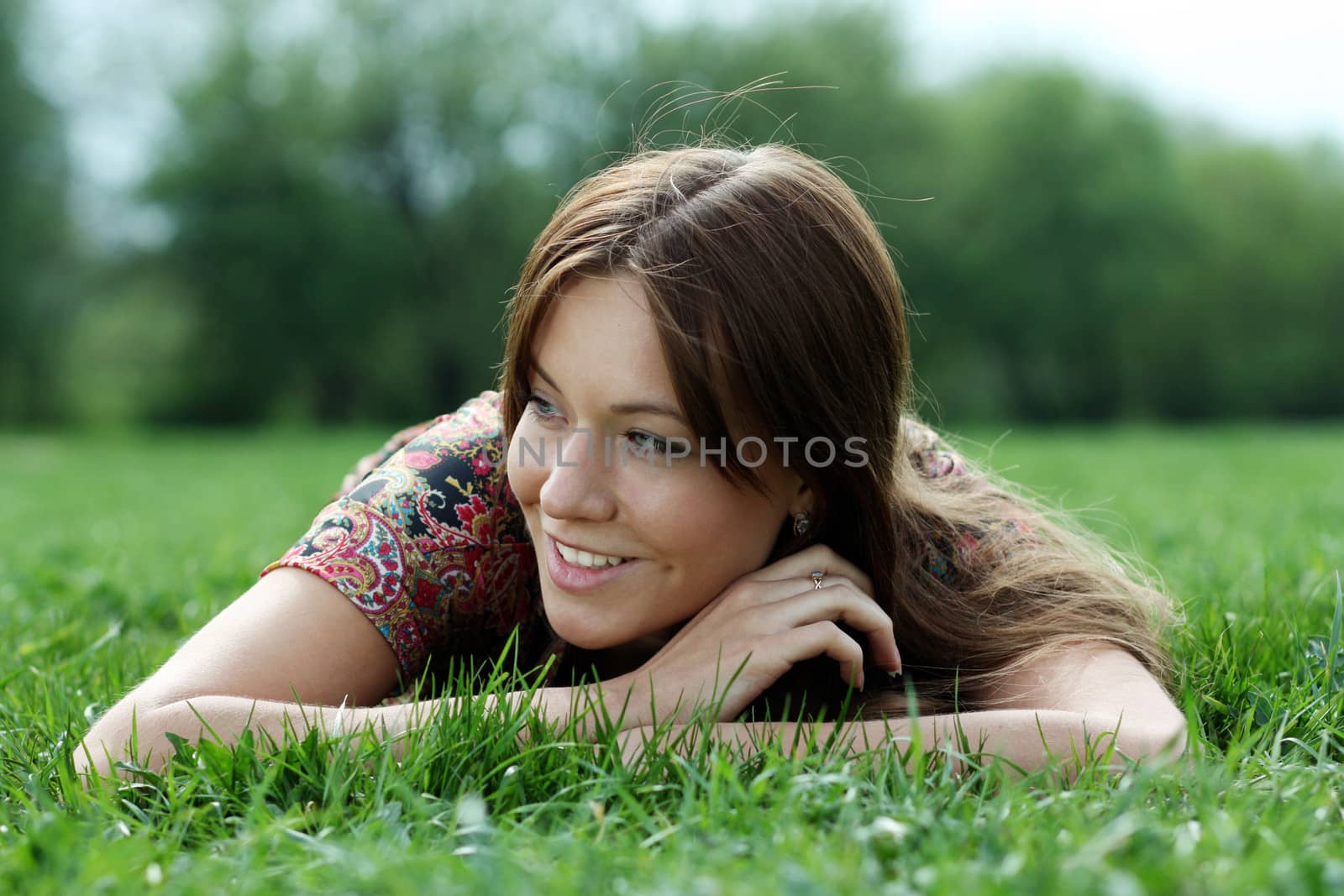 Portrait of young woman lying on a green lawn