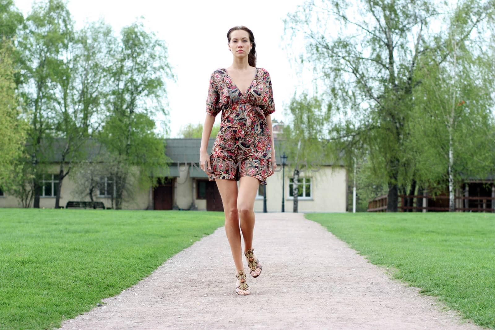 Beautiful young woman walking on the summer park