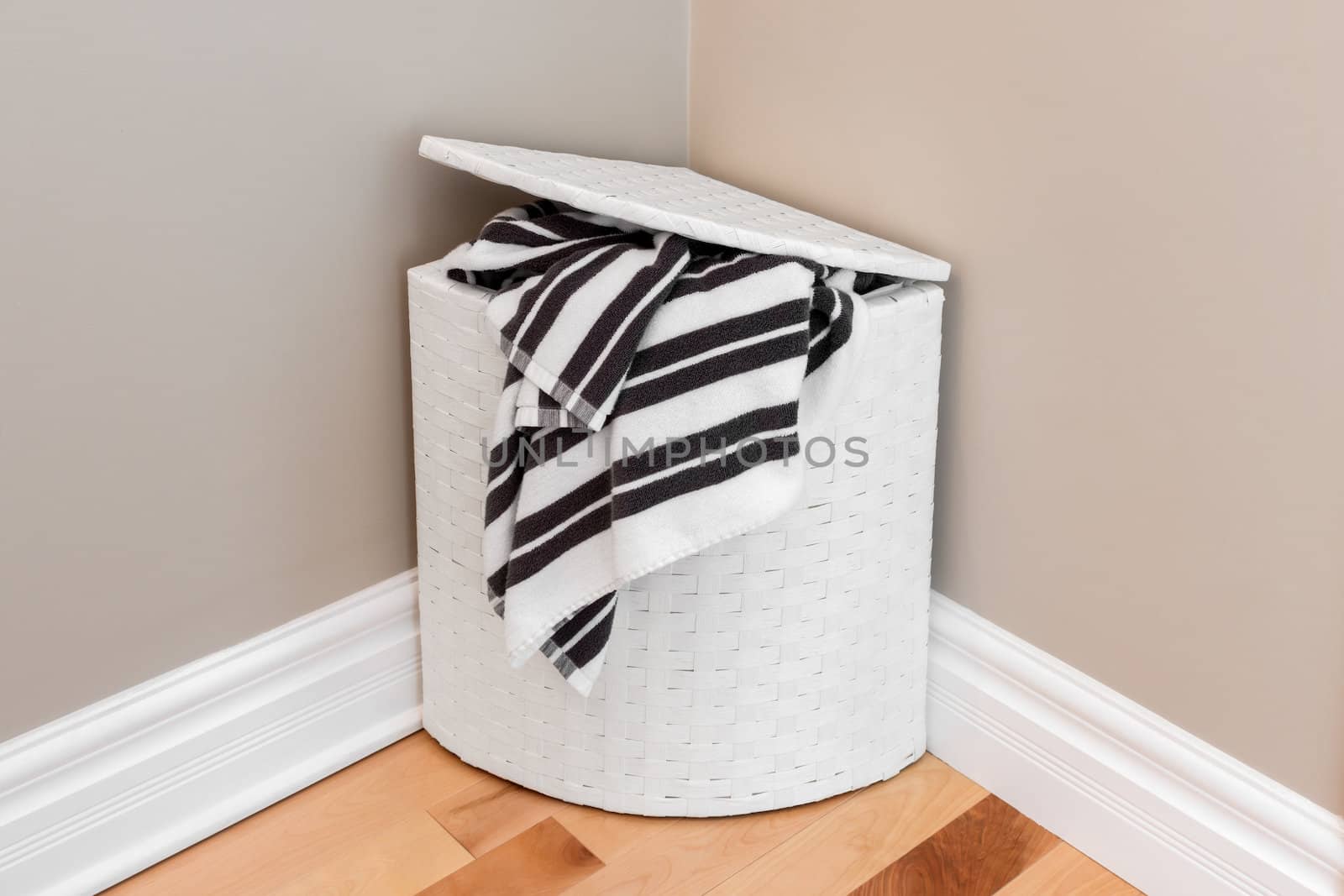 White laundry basket with striped towels in the room corner.