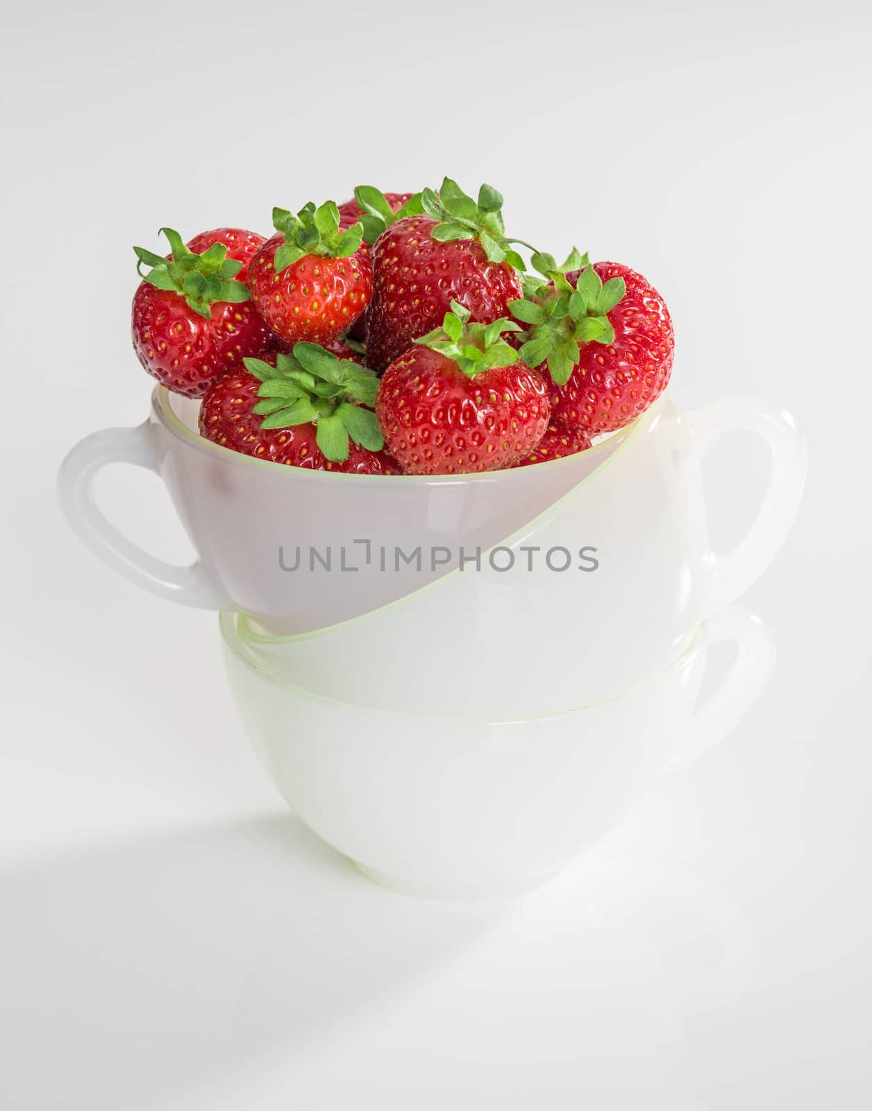 Ripe strawberries in a cup, on white background.