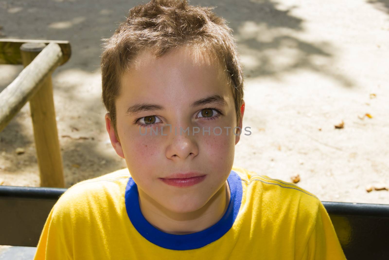 Cute boy smiling at camera in the park on a sunny day