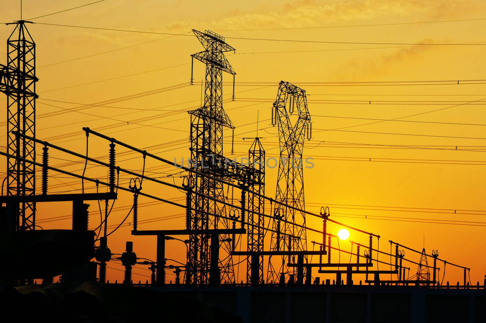 Impression network at transformer station in sunrise, high voltage up to yellow sky.