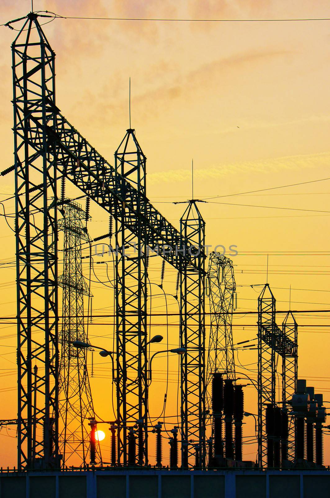 Impression network at transformer station in sunrise, high voltage up to yellow sky.