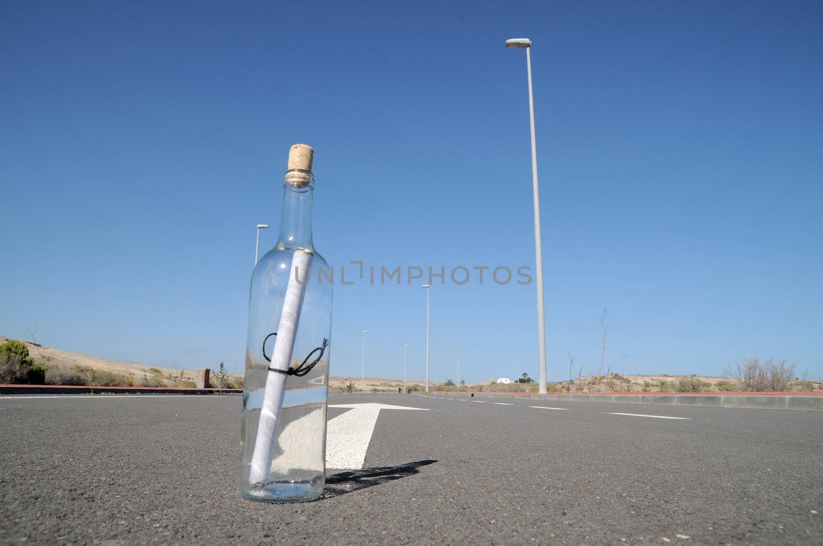 Message on a bottle and arrow on a asphalt street to the future