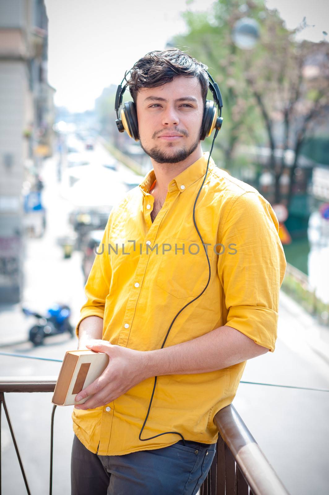 young man reading book and listening music on the balcony