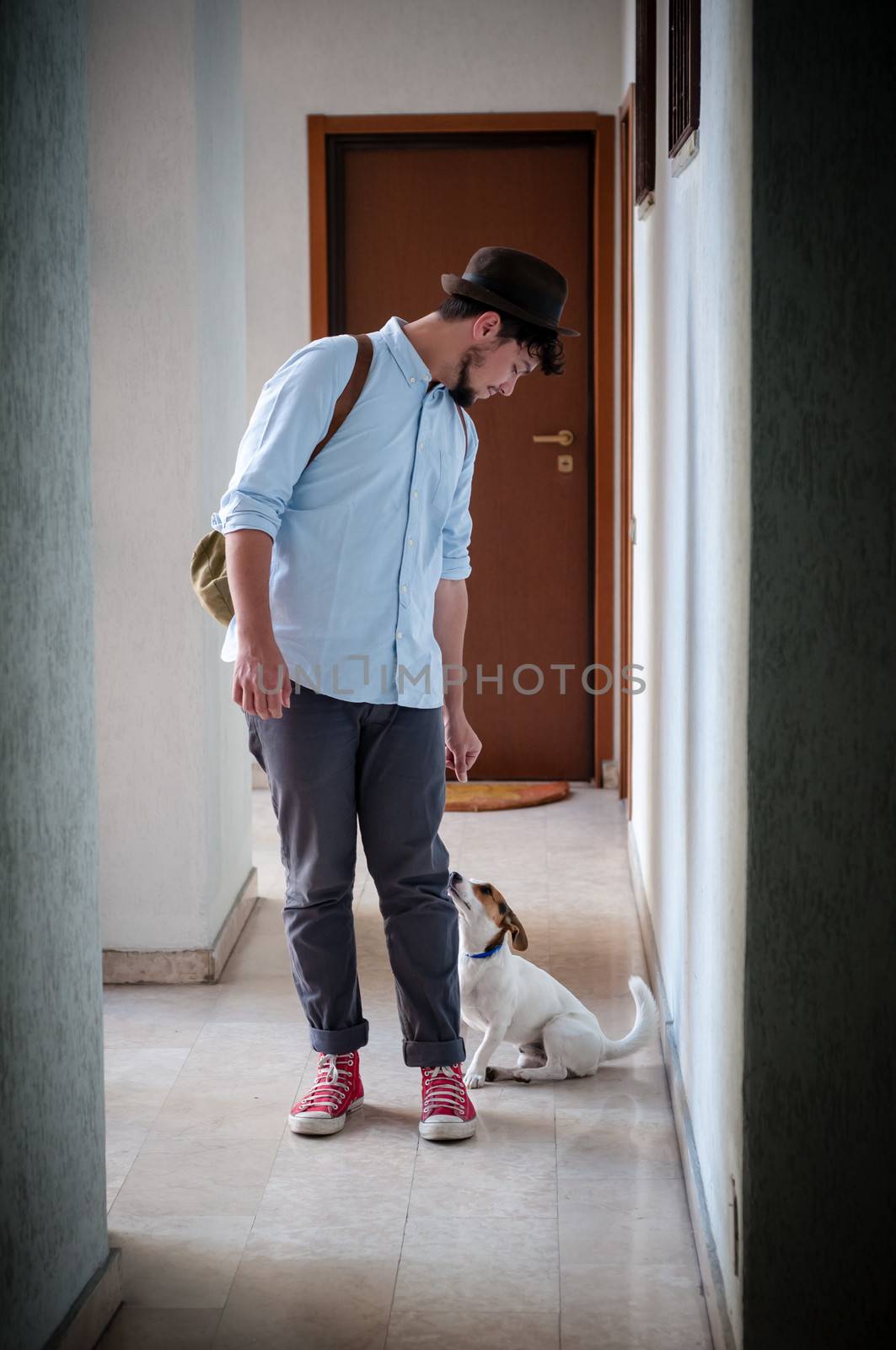 hipster young man posing with jack russell dog in a hallway