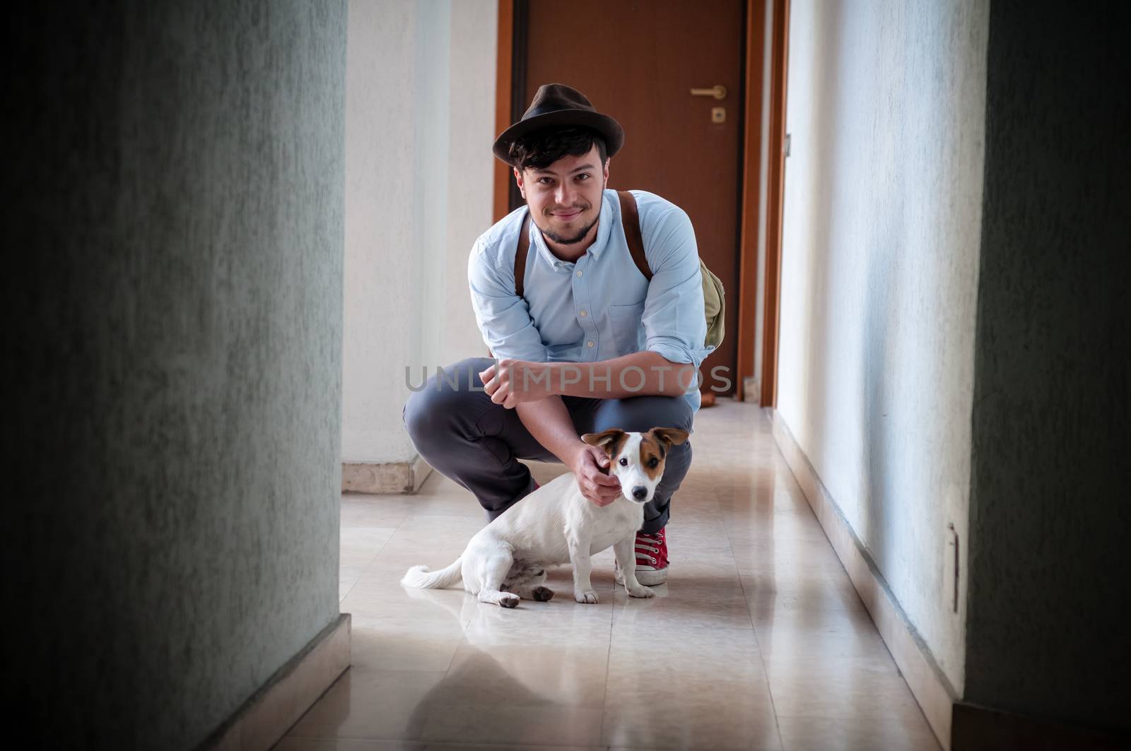 hipster young man posing with jack russell dog in a hallway
