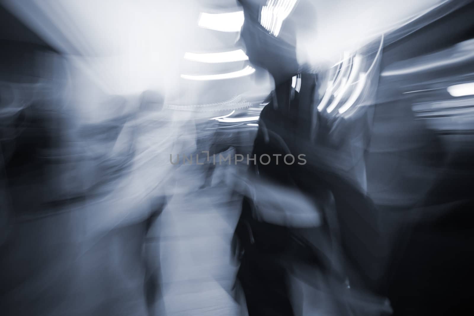 blurred motion people commuting in the underground station walkway, intentional bleach and blue tint