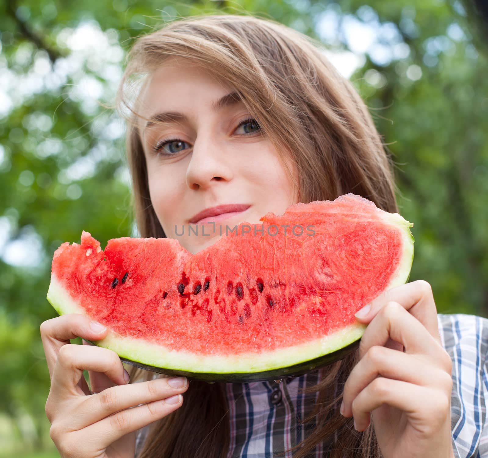 Young woman with watermelon outdoors. Focus on watermelon