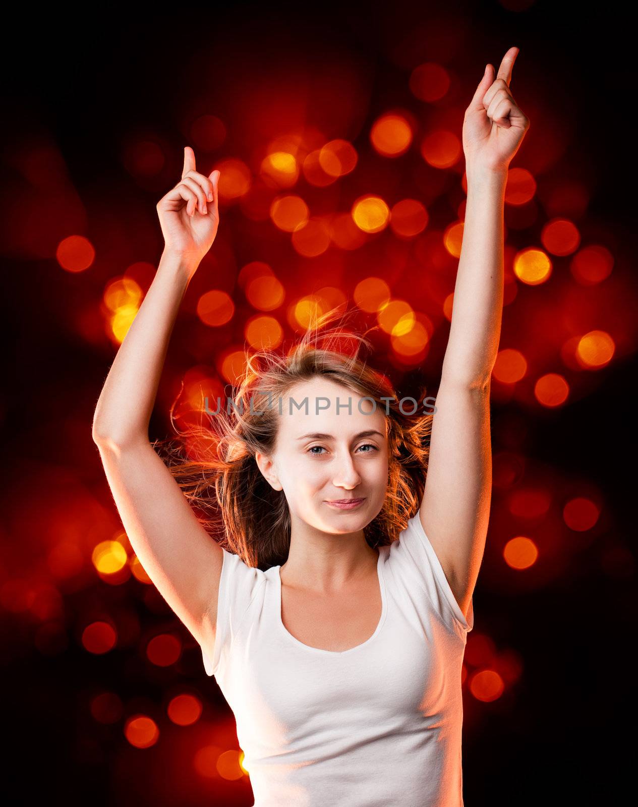 Portrait of a beautiful young woman dancing on a dark background with soft red spots