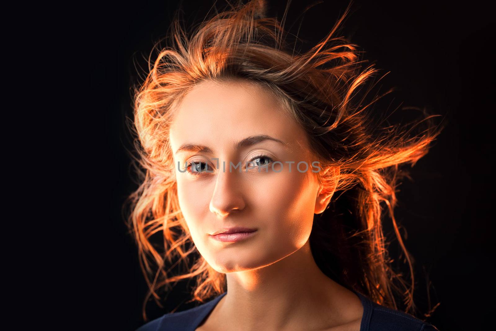 Portrait of a beautiful young woman with hair flying on dark background