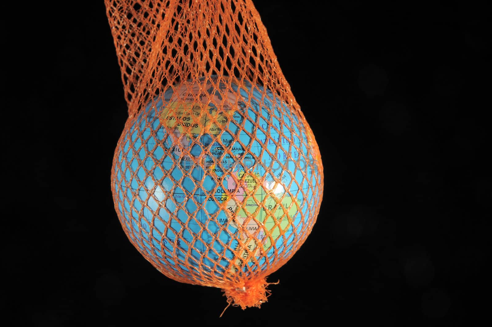 Globe in a green net on a dark black bacground