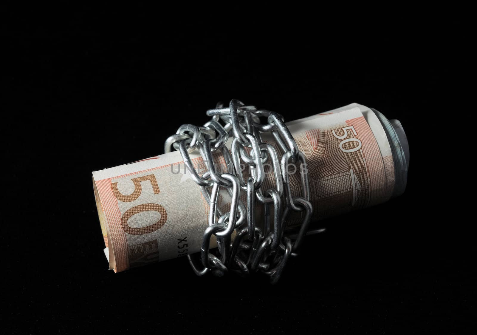 Money in chains that represents the crisis on a black background