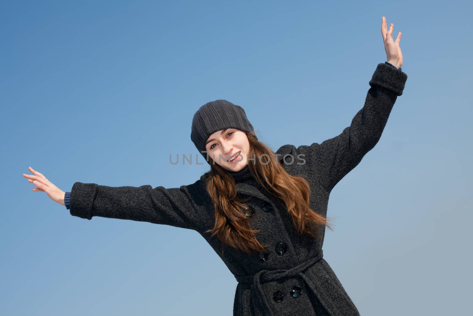  Pretty young woman with arms raised against blue sky