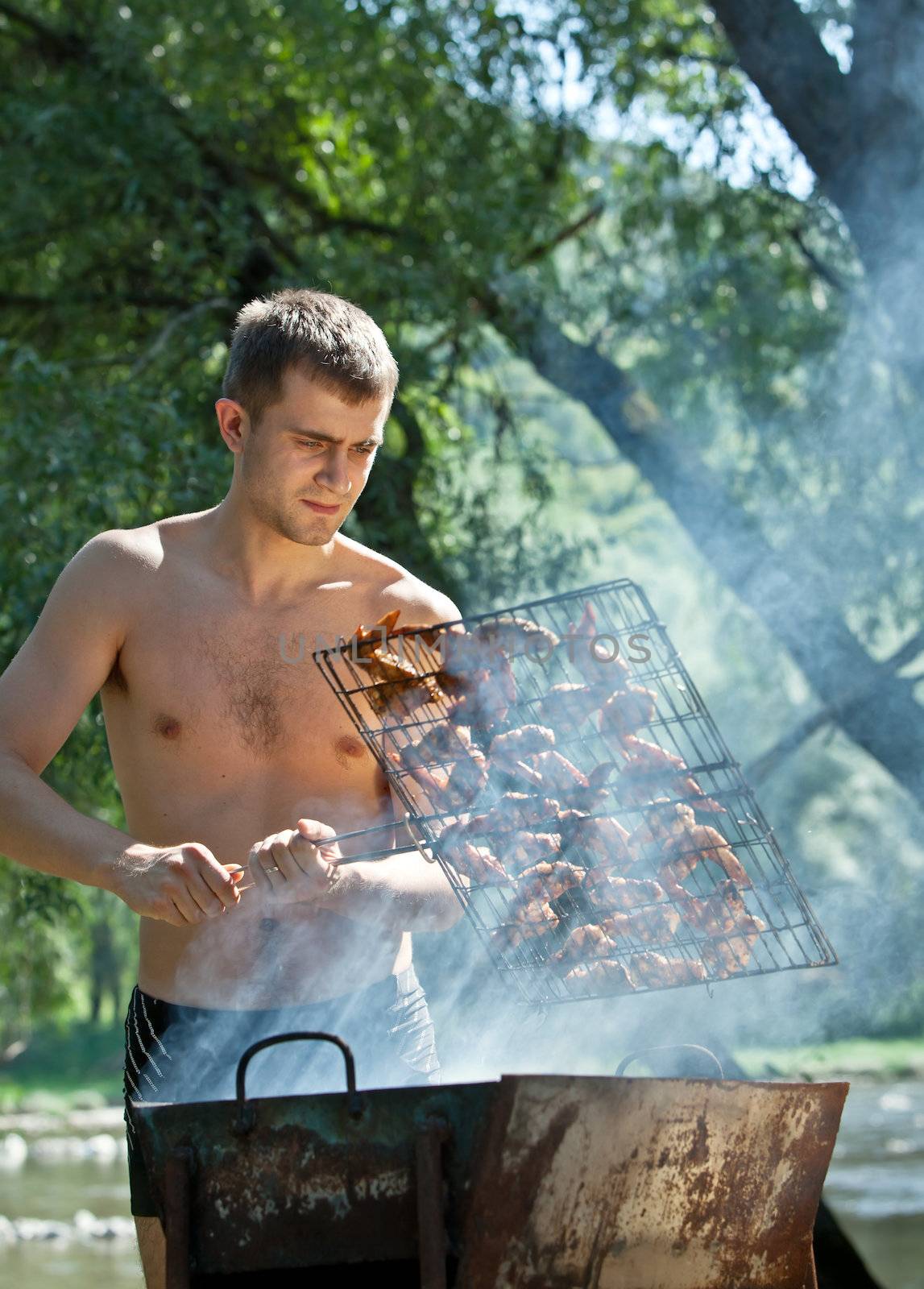 Young man preparing barbecue outdoors