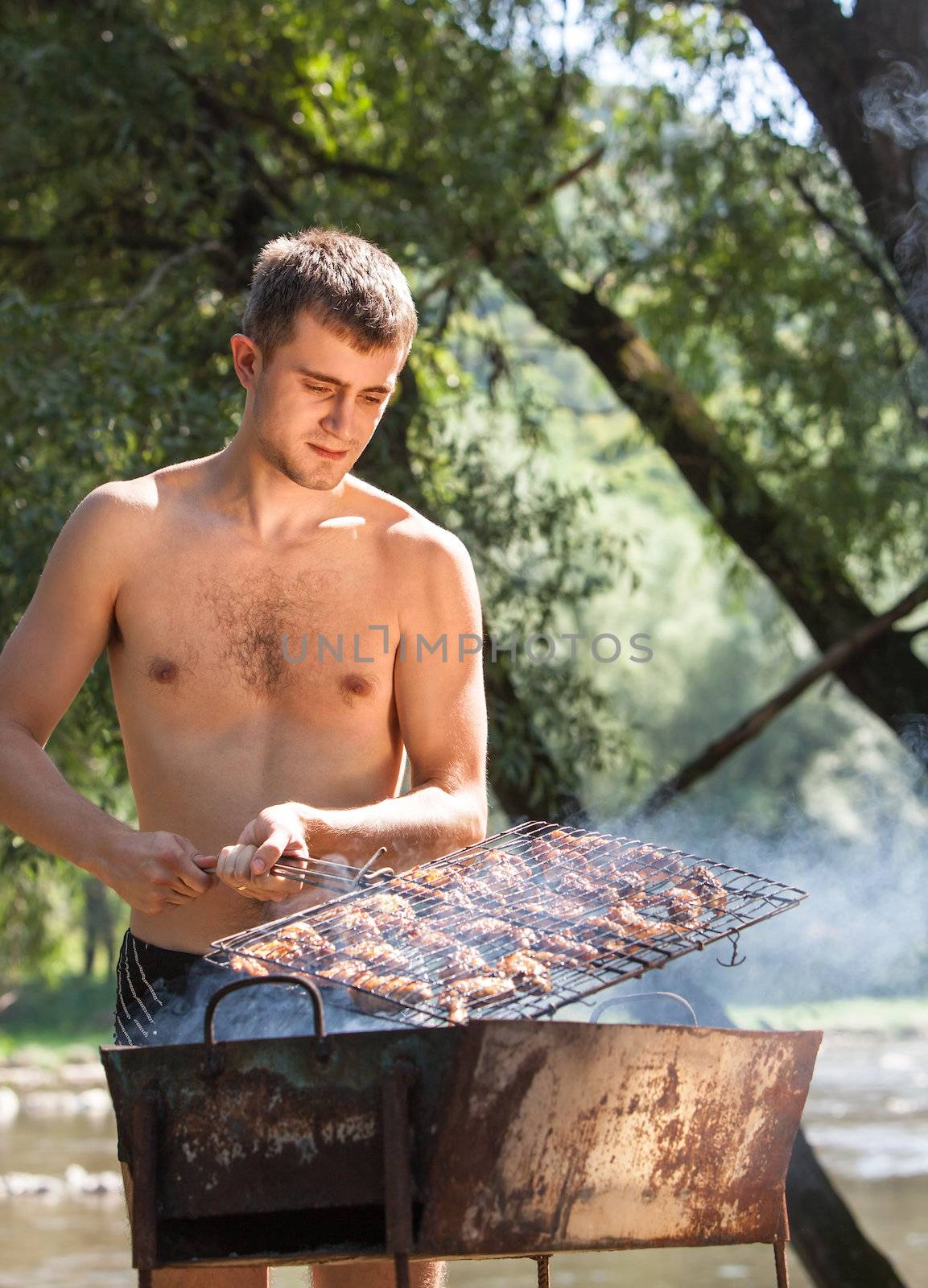 Young man preparing barbecue outdoors