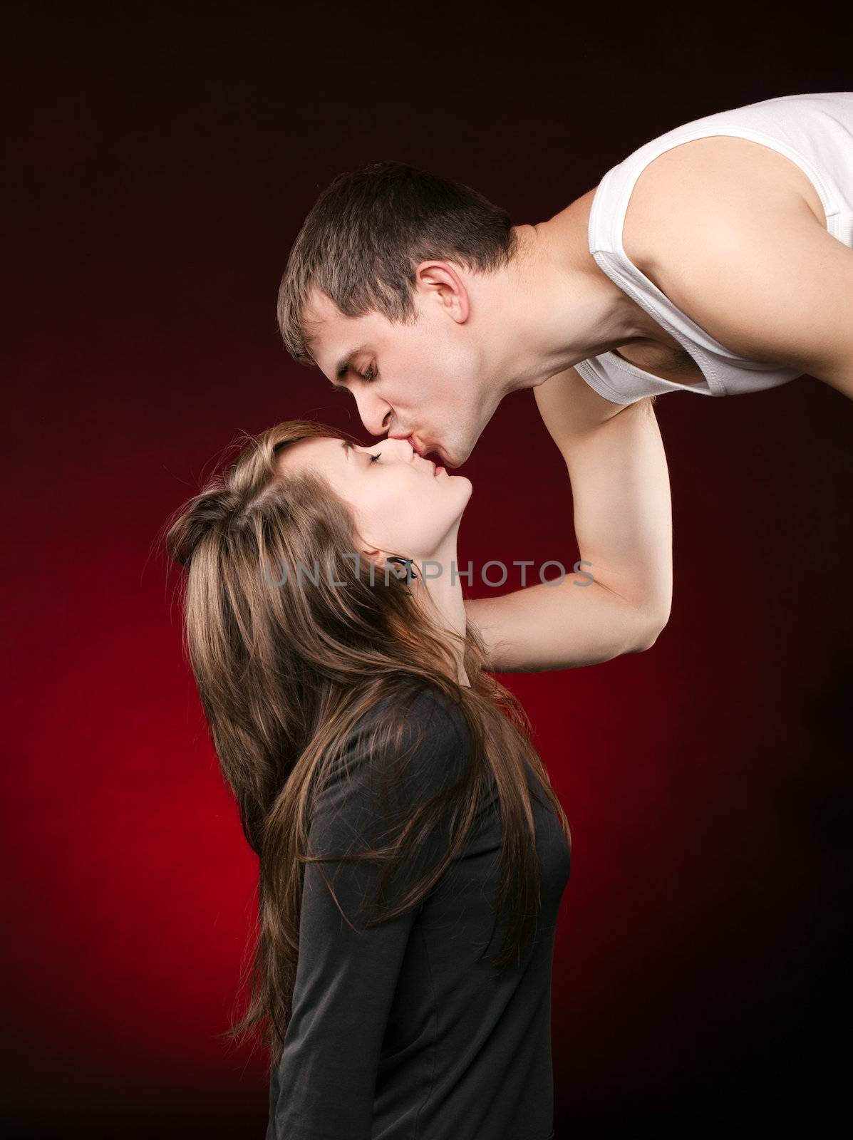 Young man kissing a girl in the nose on a red background
