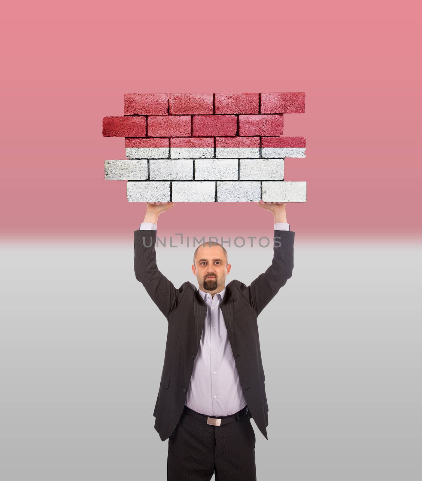 Businessman holding a large piece of a brick wall, flag of Indonesia, isolated on national flag