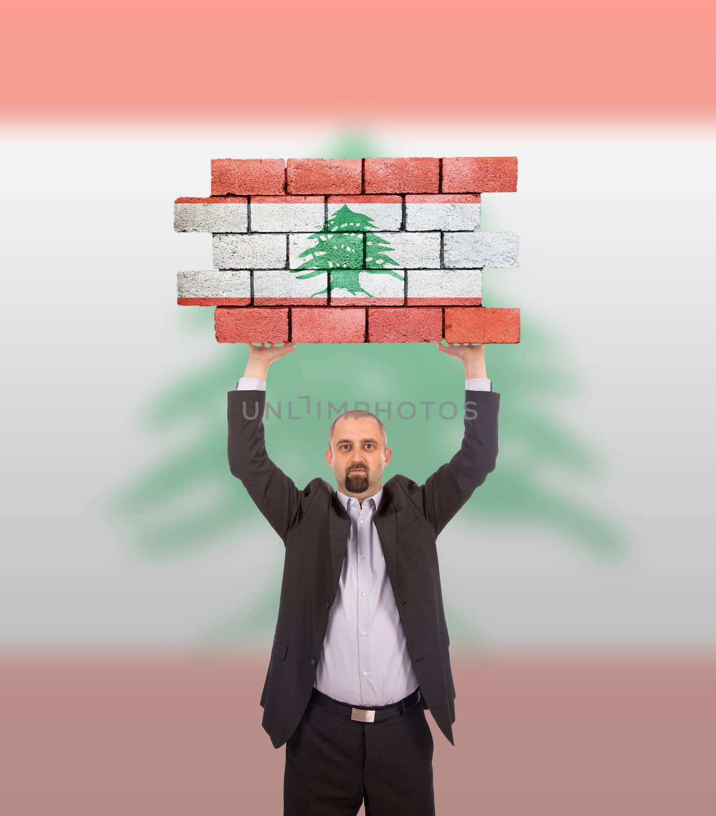 Businessman holding a large piece of a brick wall, flag of Lebanon, isolated on national flag