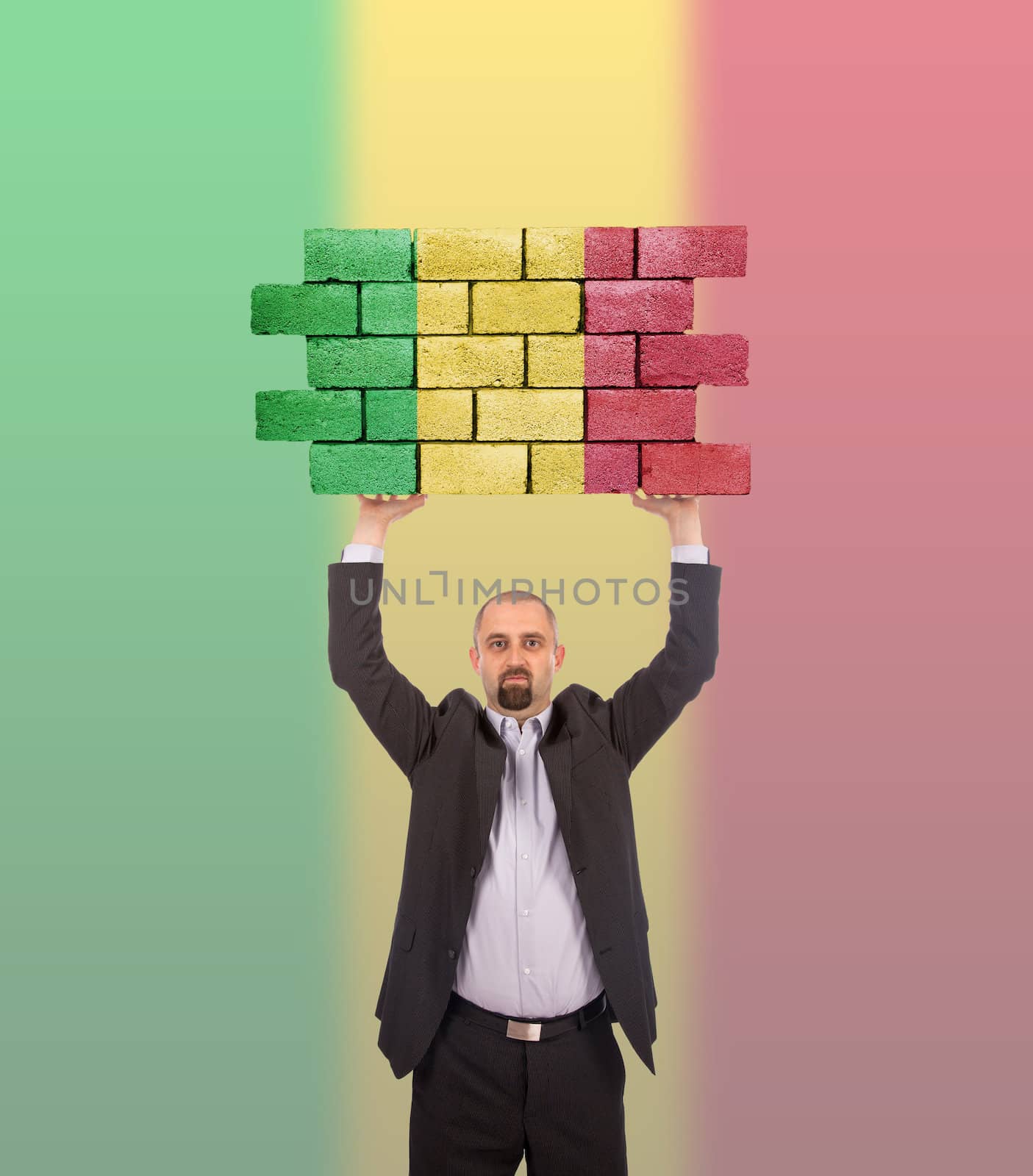 Businessman holding a large piece of a brick wall, flag of Mali, isolated on national flag