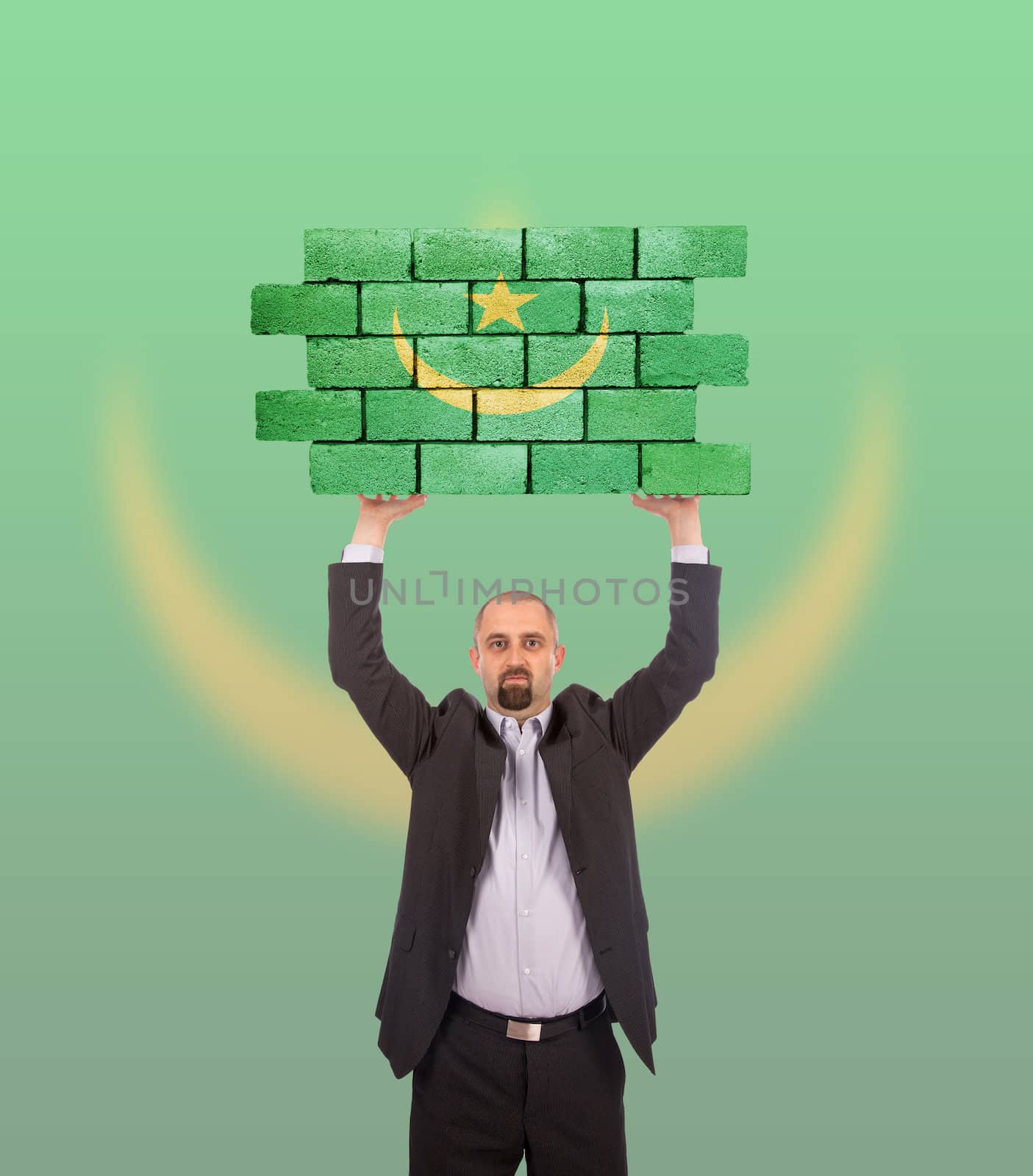 Businessman holding a large piece of a brick wall, flag of Mauritania, isolated on national flag