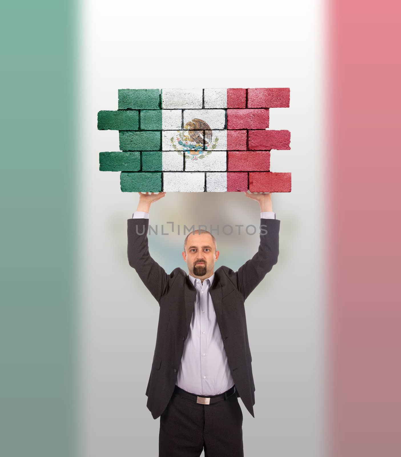 Businessman holding a large piece of a brick wall, flag of Mexico, isolated on national flag