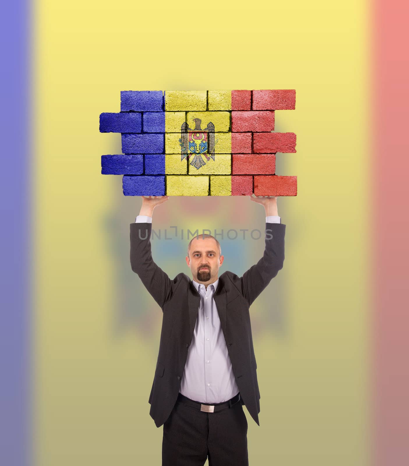 Businessman holding a large piece of a brick wall, flag of Moldova, isolated on national flag