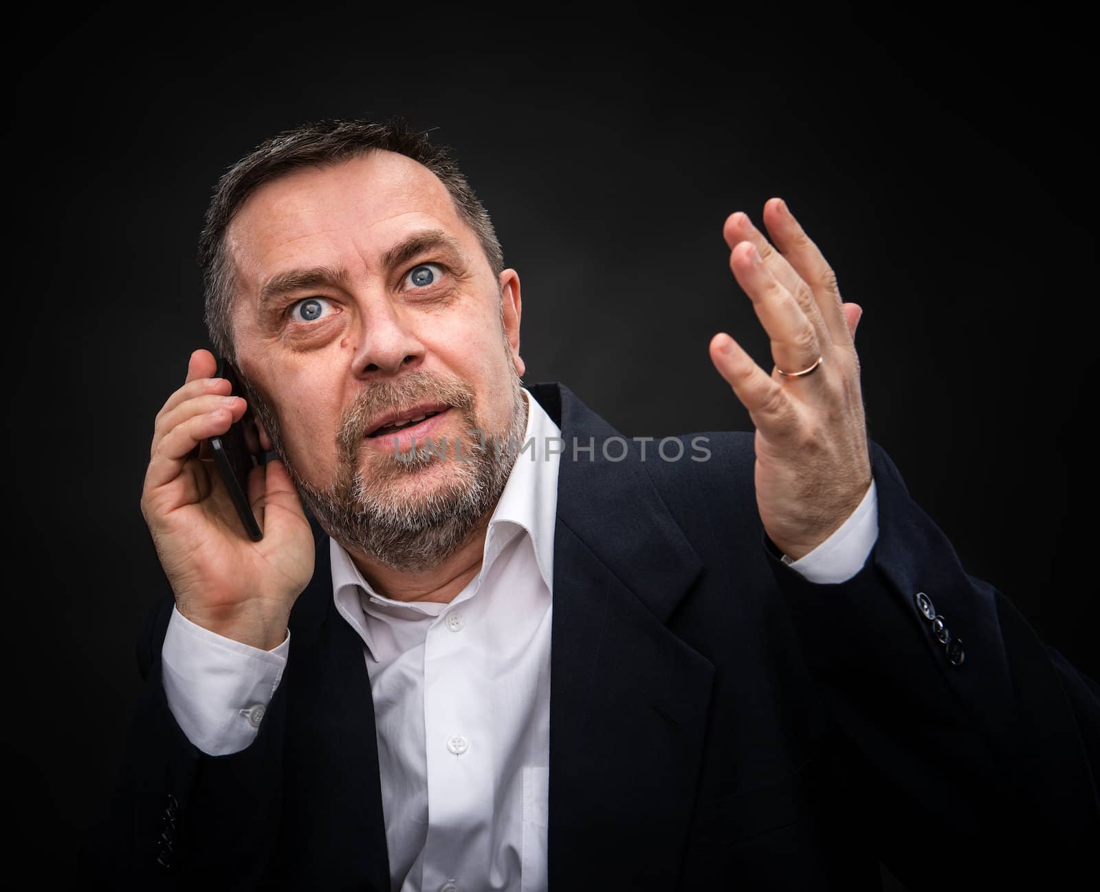 Handsome middle-aged businessman speaks on a mobile phone and gesturing