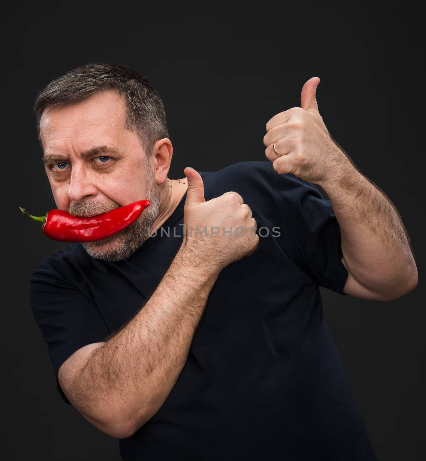 Portrait of elderly man with red pepper in his mouth