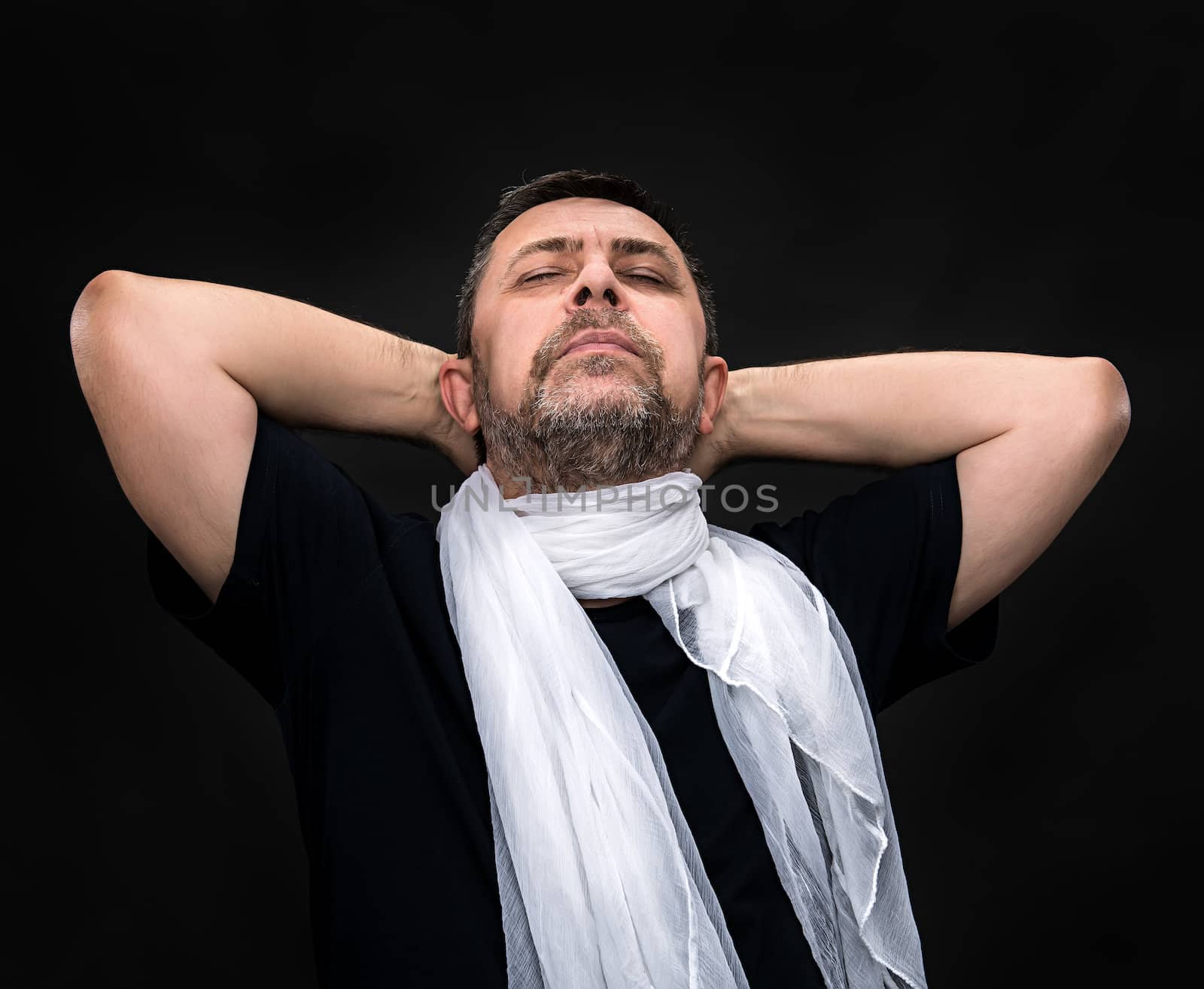 Portrait of a handsome man with a white scarf and closed eyes on a dark background